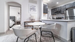 A modern kitchen with stainless steel appliances, a round dining table with chairs, and a small island. - Landing | Stylish 2BD, Pool, Clubhouse (Cincinnati)