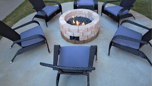A circular outdoor seating area with a fire pit in the center, surrounded by four chairs and a table. - Landing | Spectacular 1BD, Gym (Birmingham)