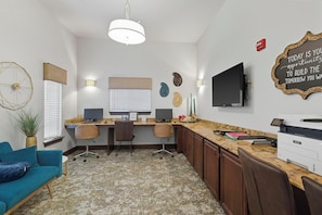 A modern office space with two desks, a large flat-screen TV, and a Xerox printer.