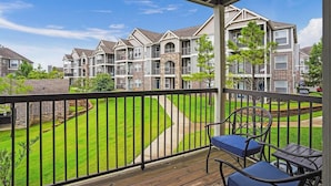 A residential building with multiple balconies, a well-maintained lawn, and a clear sky. - Landing | Stylish 1BD, Gym, Courtyard (Broken Arrow)