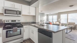 A modern kitchen with white cabinets, a built-in microwave, a stove, and a dishwasher. - Landing | Stylish 1BD, Gym, Courtyard (Broken Arrow)