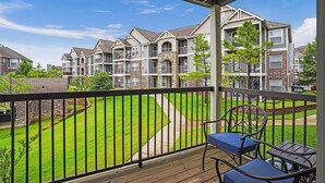 A residential building with multiple balconies, a well-maintained lawn, and a clear sky. - Landing | Amazing 2BD, Courtyard, Gym (Broken Arrow)