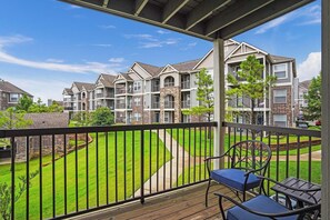 A residential building with multiple balconies, a well-maintained lawn, and a clear sky. - Landing | Beautiful 2BD, Pool, Gym (Broken Arrow)