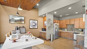 A modern kitchen with wooden cabinets, a central island, and a refrigerator. - Landing | Modern 2BD, Pool, Gym (Jenks)