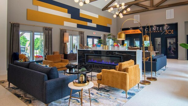 A spacious lobby with a fireplace, modern furniture, and a sign for Center Apartments 301. - Landing | Stunning 1BD, Clubhouse, Gym (Belton)