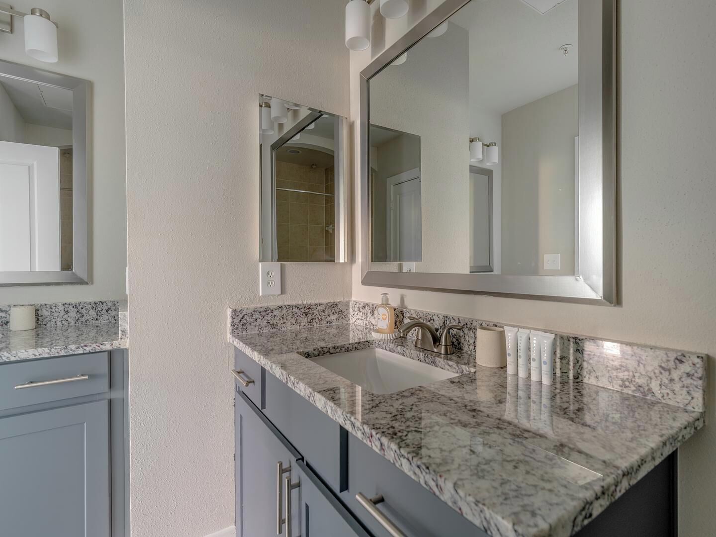 Une salle de bain avec un comptoir en marbre, un lavabo et deux miroirs.