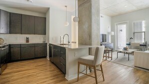 A modern kitchen with dark cabinets, a central island, and pendant lighting. - Landing | Stylish 2BD, Gym, Pool (Durham)