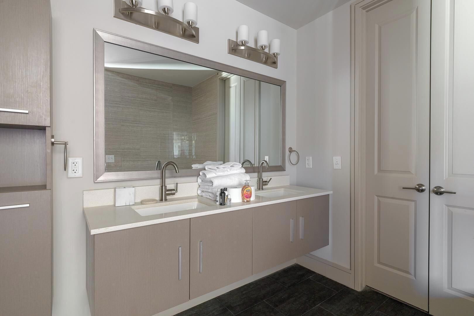Un bagno moderno con un ampio specchio, due lavabi e un portascopevoli.