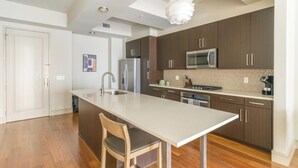 Une cuisine moderne dotée d’un îlot central, d’appareils électroménagers en acier inoxydable et d’un revêtement de sol en bois.