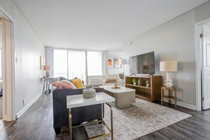 A modern living room with a sofa, coffee table, TV, and lamps.