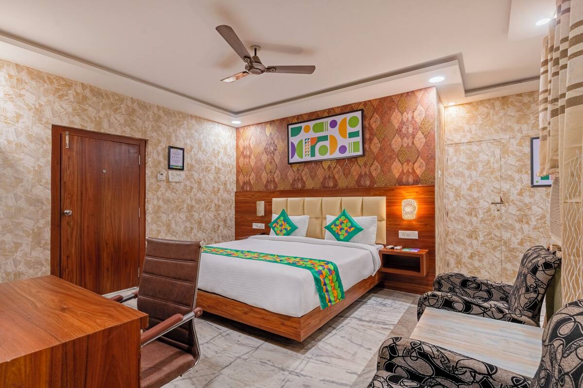 Une chambre d’hôtel avec un lit en bois, un bureau, une chaise et un canapé.