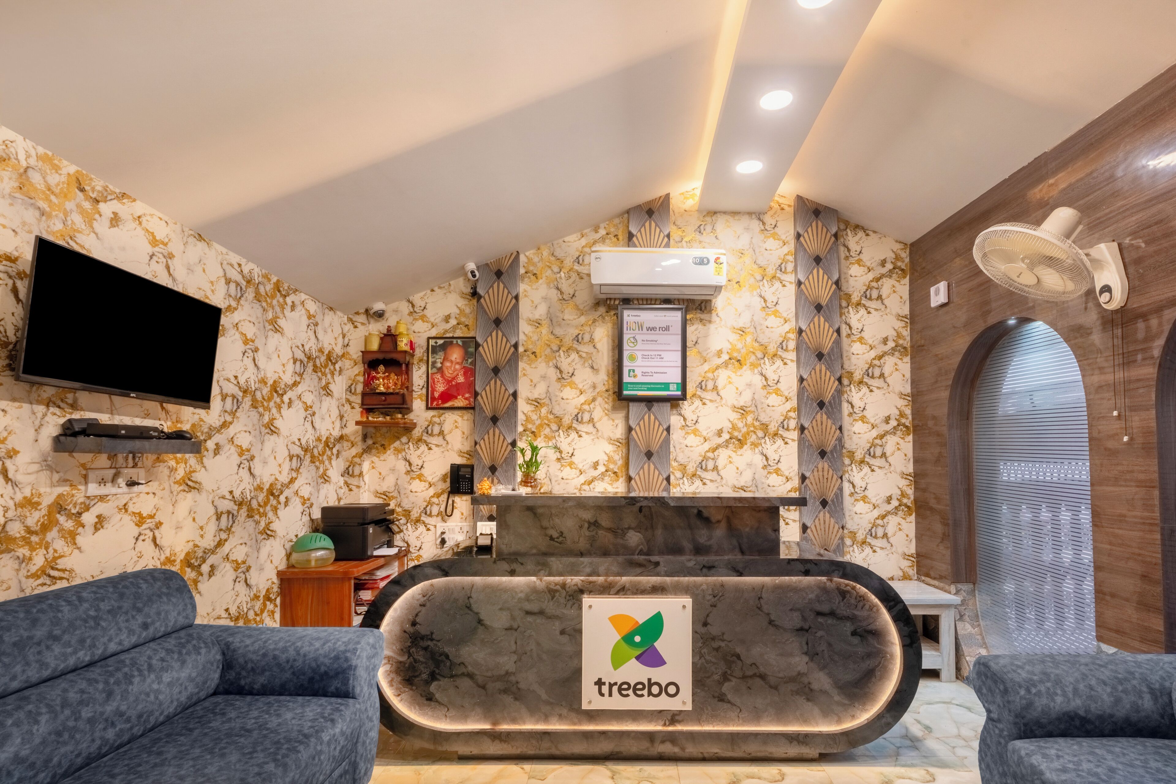 A reception area with a marble counter, a television, and a wall-mounted air conditioner.