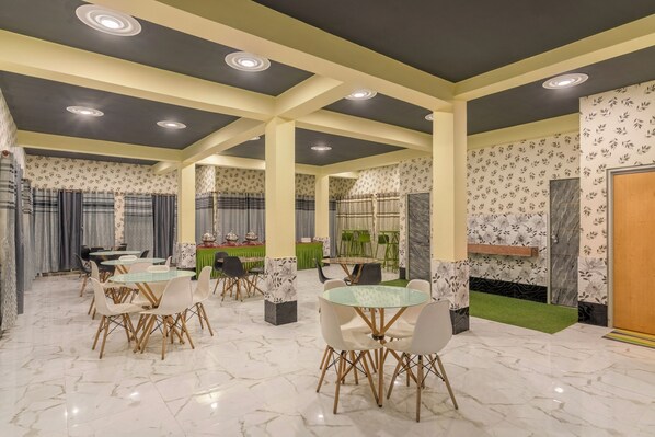 A spacious dining area with marble flooring, multiple tables and chairs, and decorative elements like curtains and wall patterns. - Treebo Una Regency - Near AIIMS Patna (Patna)