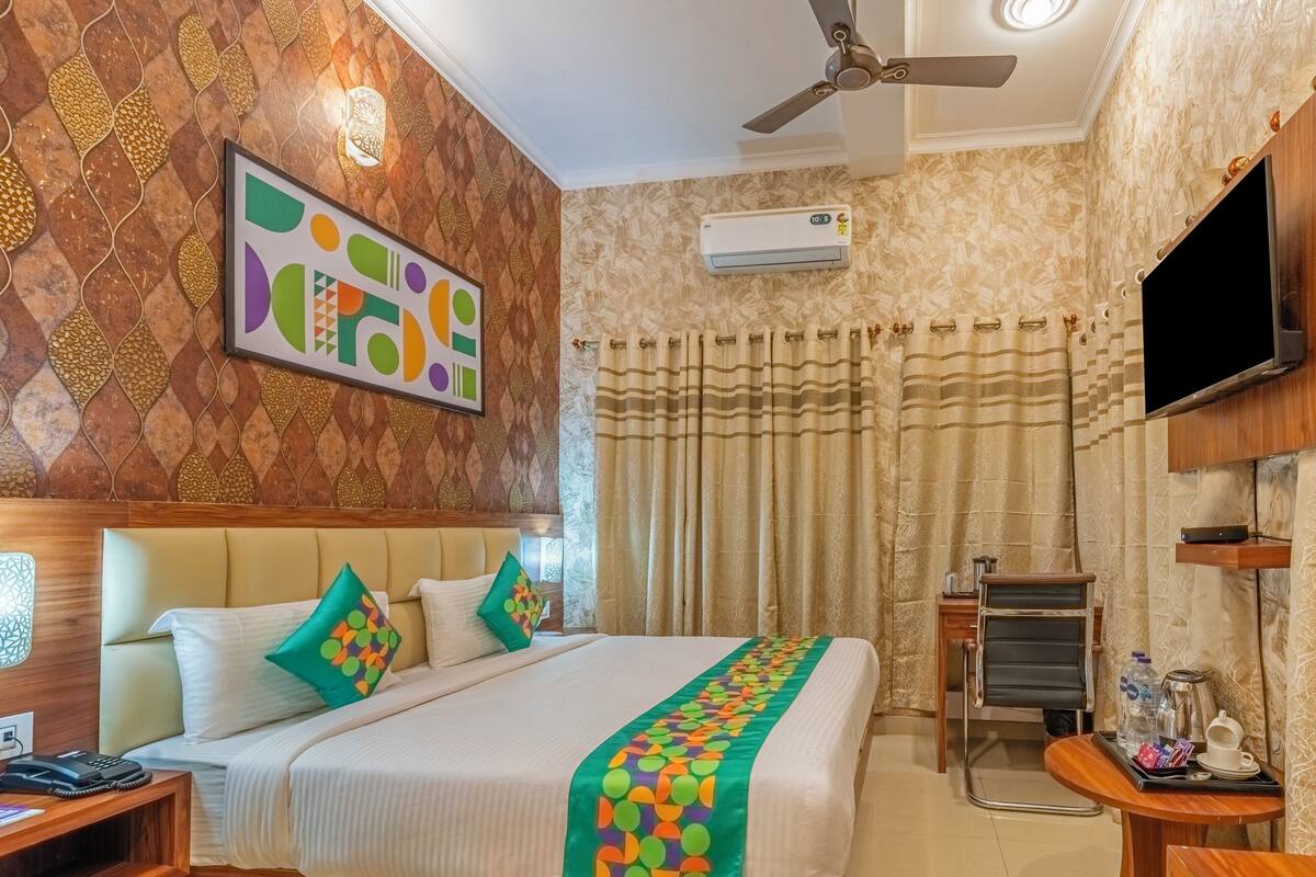 Une chambre d’hôtel équipée d’un lit, d’une télévision, d’un climatiseur, d’un bureau avec un téléphone et d’une œuvre d’art accrochée au mur.
