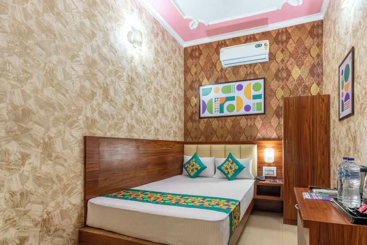 Une chambre d’hôtel avec un lit en bois, une table de chevet, une armoire et un climatiseur fixé au mur.