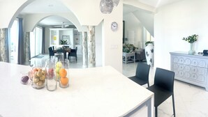 A modern kitchen with a central island, white cabinetry, and a view to the dining area.