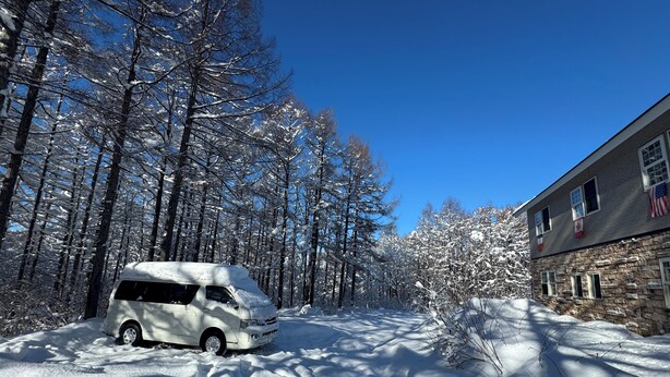 Una carretera nevada con una furgoneta blanca estacionada al borde.