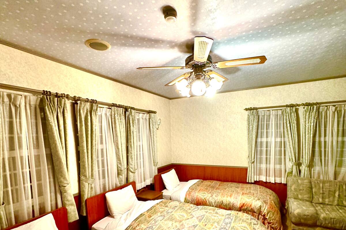 A hotel room with two beds, a ceiling fan, and curtains.