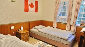 A room with a bed, a nightstand, a clock, a Canadian flag, and a window with curtains.