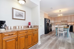 A modern kitchen with wooden cabinets, a black refrigerator, and a dining area with a table and chairs.