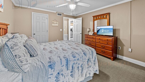 Ein Schlafzimmer mit Bett, Kommode, Deckenventilator und Fernseher.