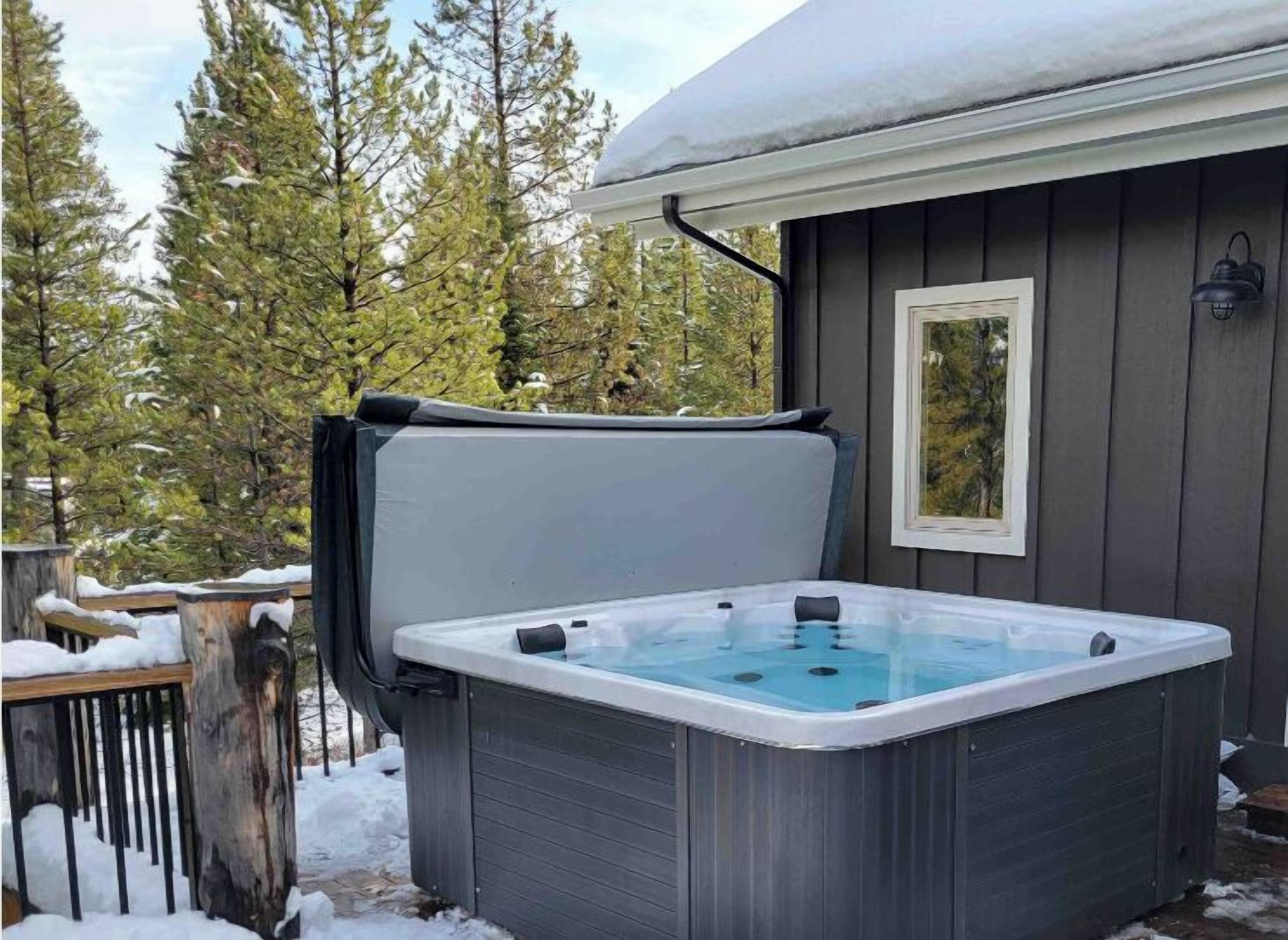 A hot tub in a covered outdoor area with a wooden deck and snow on the ground.