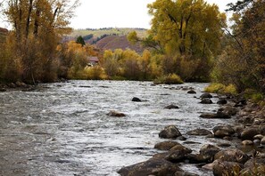 Une rivière bordée de rochers et d’arbres aux couleurs automnales.
