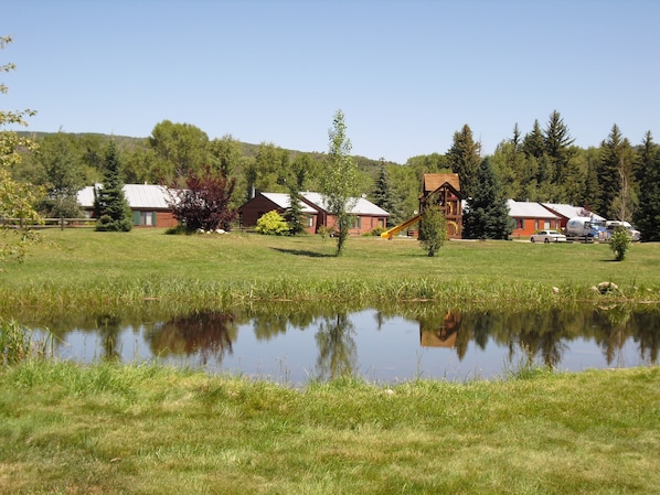 A lakeside property with cabins, a playground, and a pond.