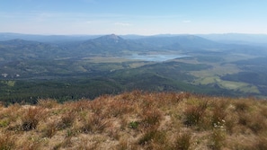 A panoramic view of a mountainous landscape with a lake and forested areas.