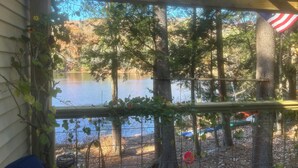 A view through a wooden pergola with a metal fence, overlooking a lake with trees and an American flag.