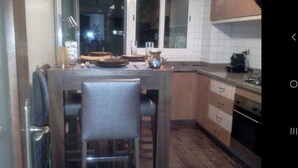 Une cuisine de taille réduite avec un îlot central, des meubles en bois et des appareils électroménagers de base.