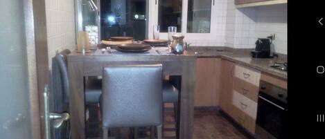 Una cocina compacta con una isla central, armarios de madera y electrodomésticos básicos.
