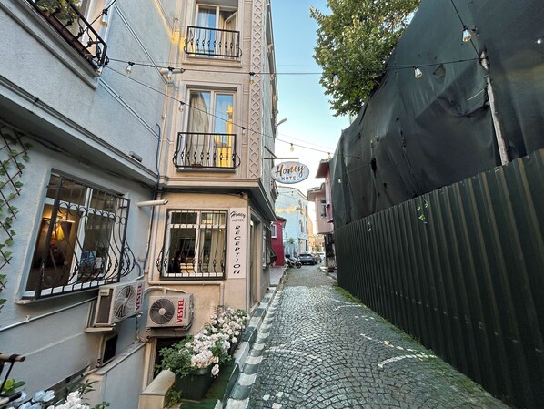 A narrow cobblestone street lined with buildings, including a hotel with a reception sign. - Honey Hotel (Istanbul)