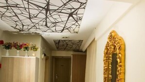 A hallway with a patterned carpet, a wooden wardrobe, a decorative ceiling, and a large ornate mirror. - Honey Hotel (Istanbul)