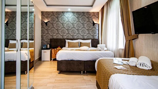 A hotel room with two beds, a flat-screen TV mounted on the wall, a minibar, and a mirror. - Honey Hotel (Istanbul)