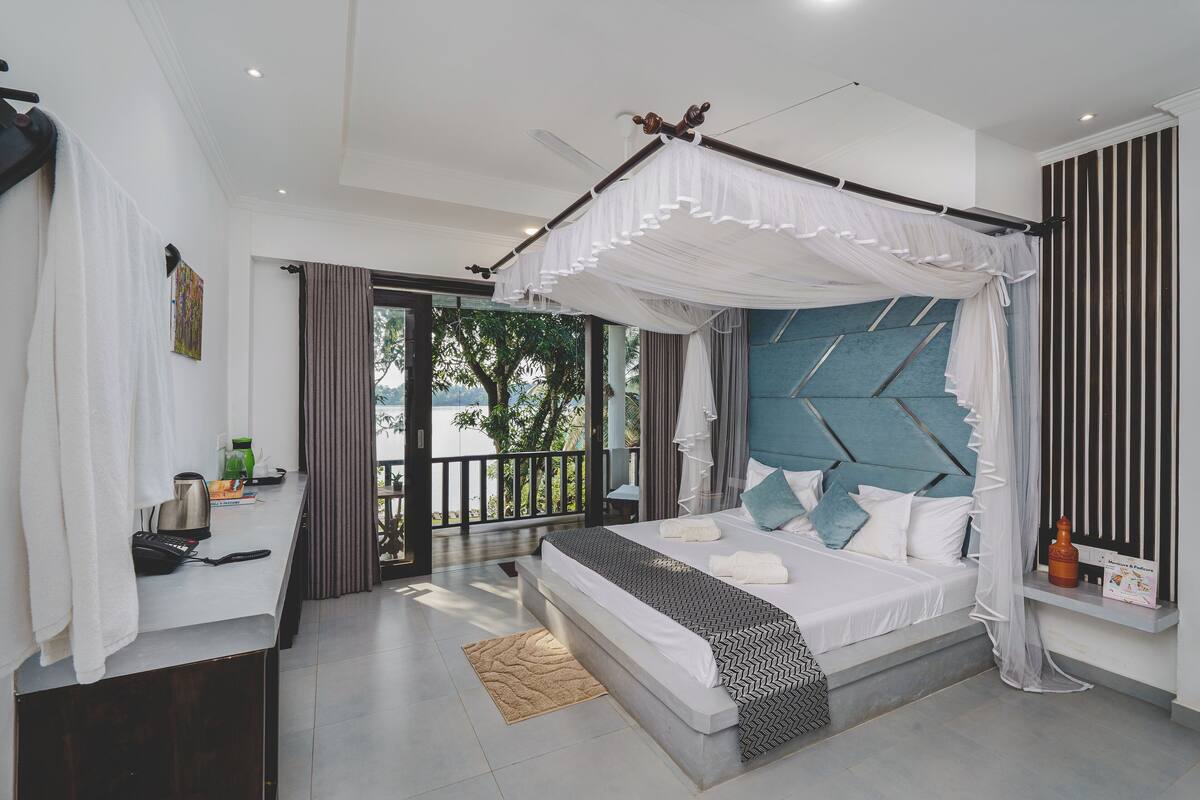 A modern bedroom with a canopy bed, a view of the outdoors, and a balcony.