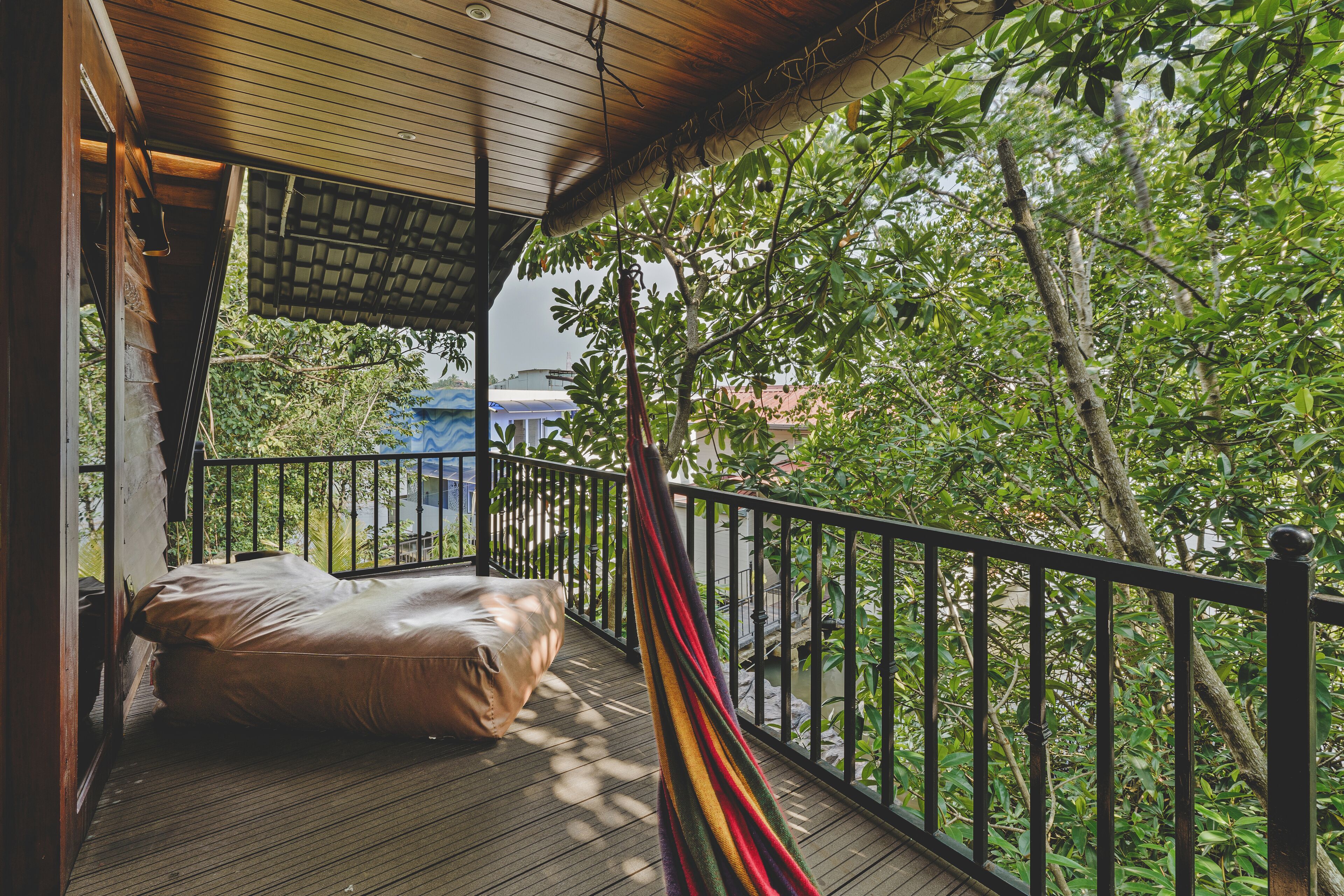 Eine Holzterrasse mit einer Hängematte und einem Sitzsack, umgeben von üppiger Vegetation.