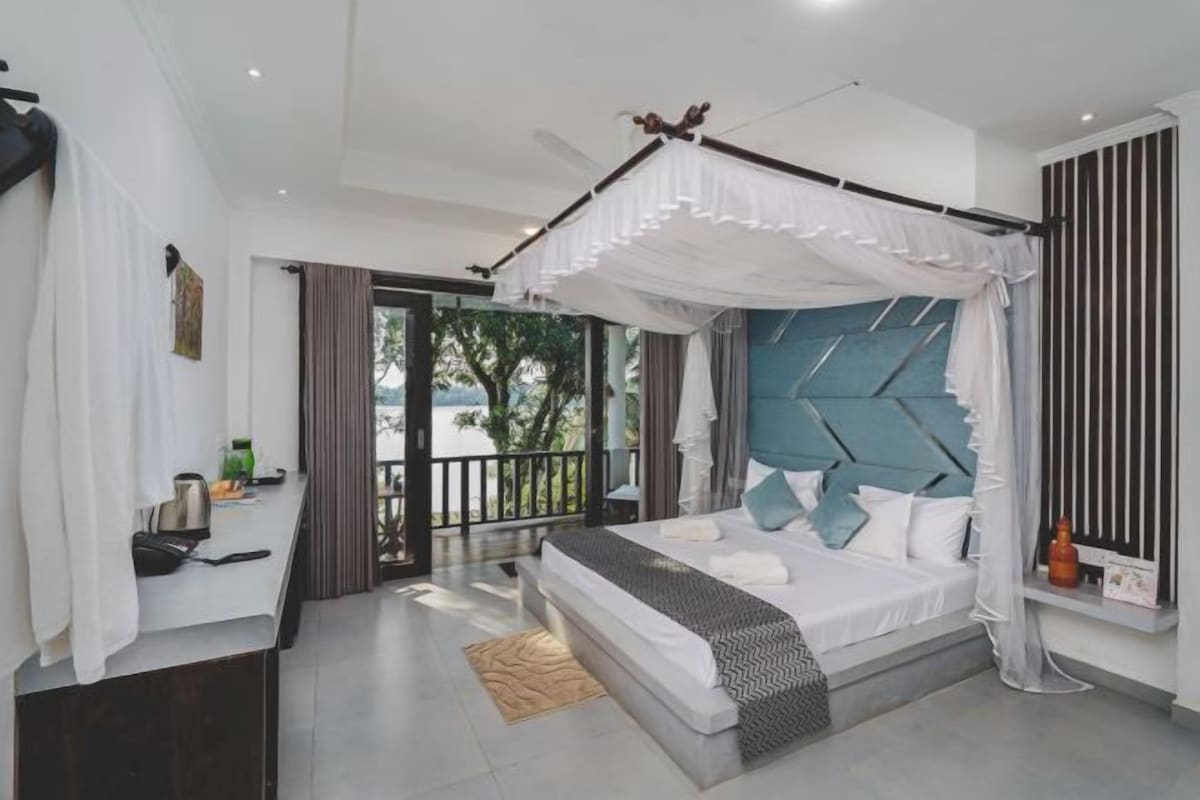 A modern bedroom with a canopy bed, a view of the outdoors, and a balcony.
