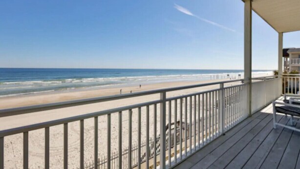 A beach view from a wooden deck with a railing, overlooking the ocean. - Ocean Front King Suite #215 (New Smyrna Beach)