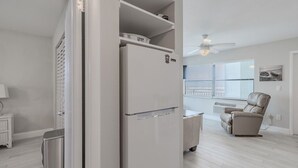 A kitchen with a refrigerator, a dining table, and a chair. - Ocean Front King Suite #215 (New Smyrna Beach)
