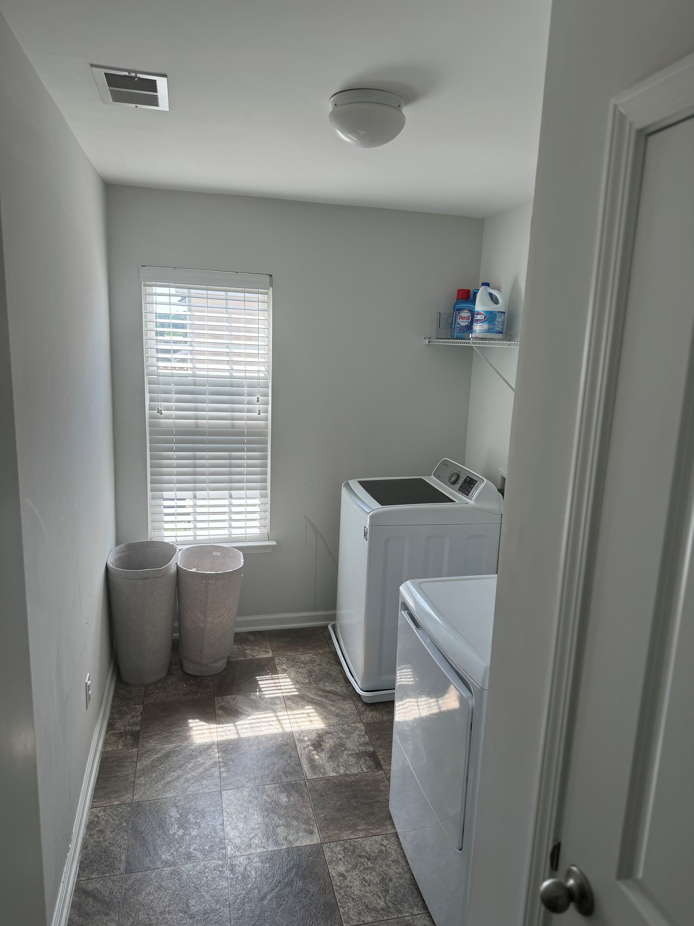 A laundry room with a washing machine, dryer, and two laundry baskets.
