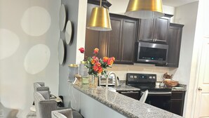 Una cocina moderna con armarios de madera oscura, encimera de granito y una isla central con taburetes de bar.