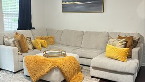 Una sala de estar con un sofá gris, una mesa de centro y un cuadro grande en la pared.