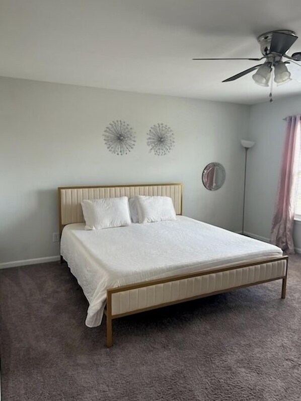 A bedroom with a bed, a ceiling fan, and two wall decorations. - Spacious 5-bedroom house in lovely North Charleston!! 20mins to Downtown (North Charleston)