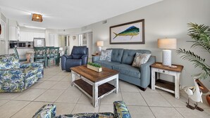 A living room with a sofa, coffee table, and a dining area with chairs and a table.