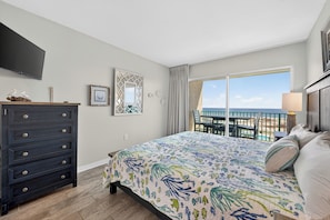 A bedroom with a bed, dresser, TV, and a balcony with a view. - Gulf Shores Plantation-Palms 6511 (Gulf Shores)