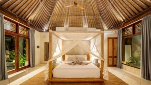 A spacious bedroom with a four-poster bed, large windows, and a high ceiling with a woven design.
