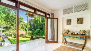 A spacious room with a large sliding glass door leading to a lush garden.