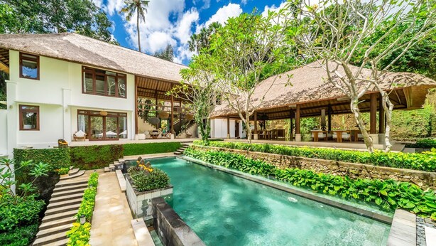 A modern house with a swimming pool, a covered outdoor seating area, and a well-maintained garden.