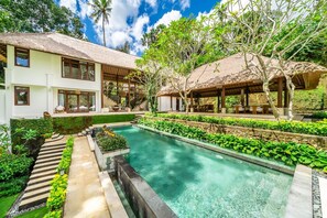 Una casa moderna con piscina, un área de estar techada al aire libre y un jardín bien cuidado.
